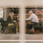 Man and Woman Sitting on Black Wooden Chairs