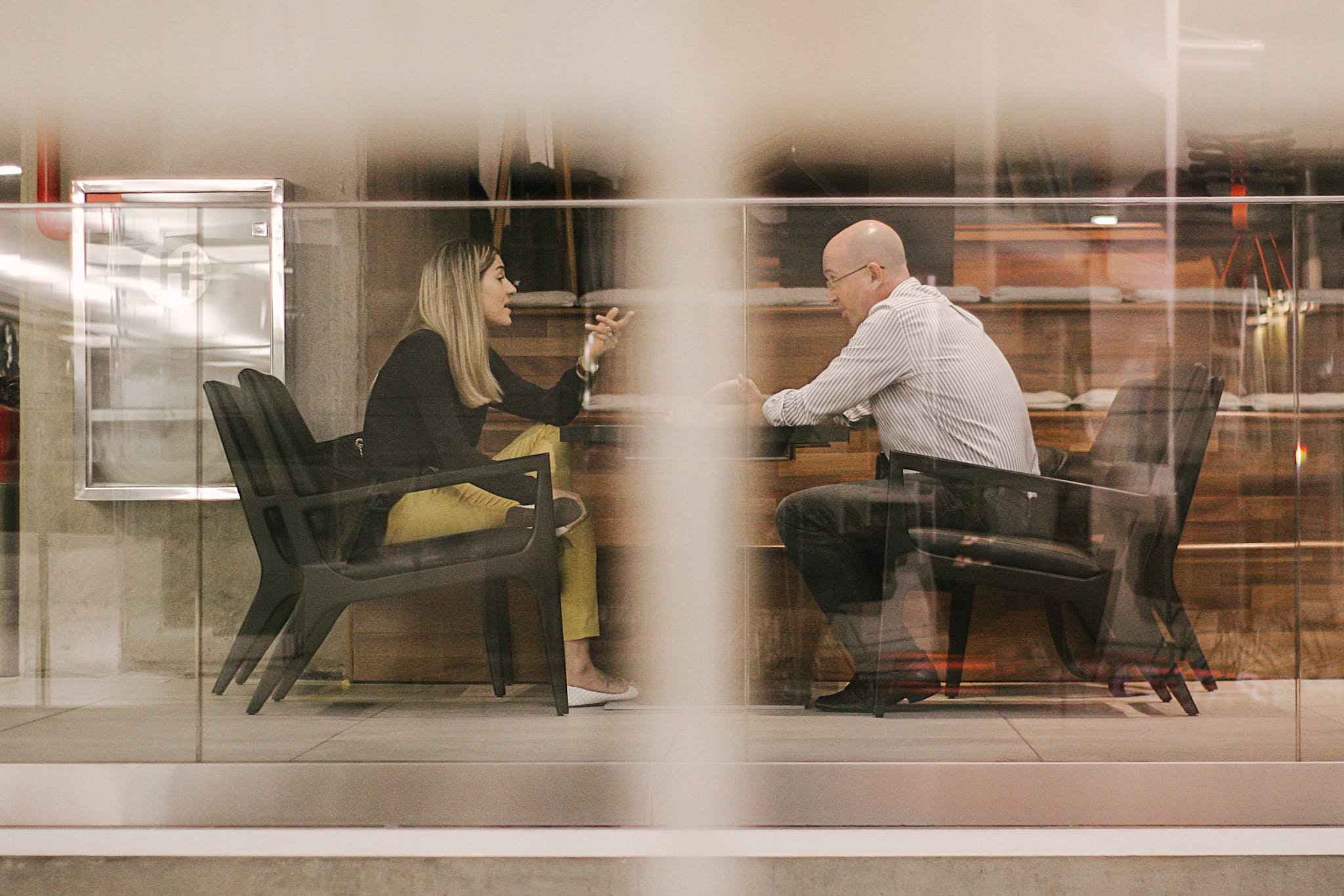 Man and Woman Sitting on Black Wooden Chairs